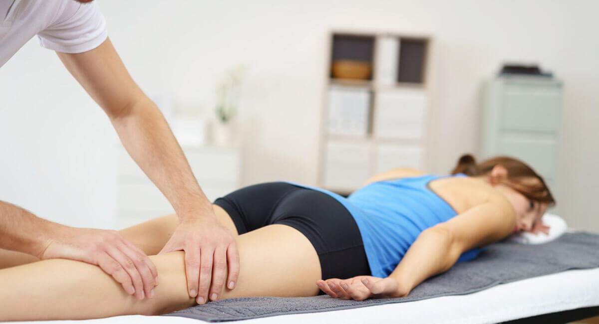 a man massaging leg of a woman that is laying down