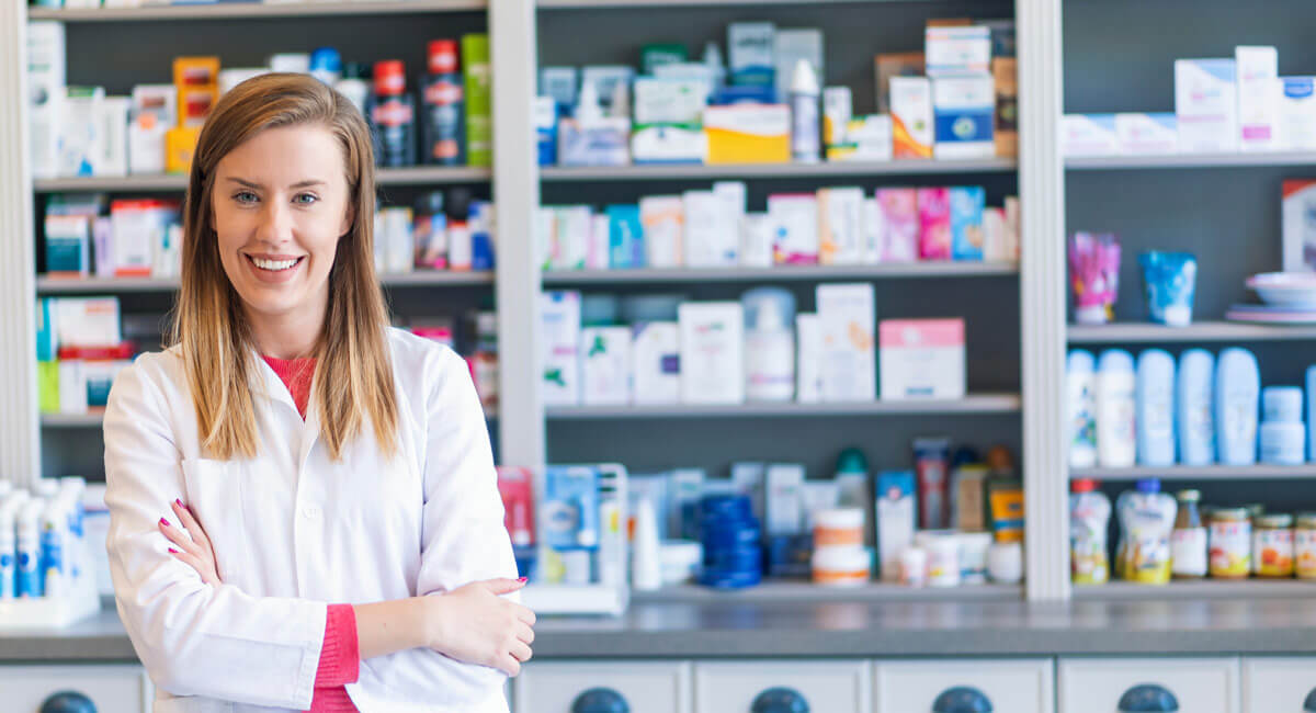 a woman smiling dressed in doctor's gown in pharmacy